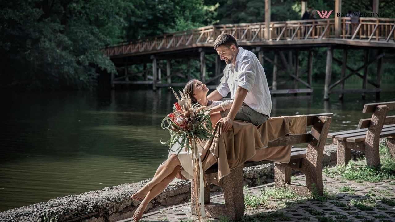 Couple sitting by a lake, holding a decorative bouquet.