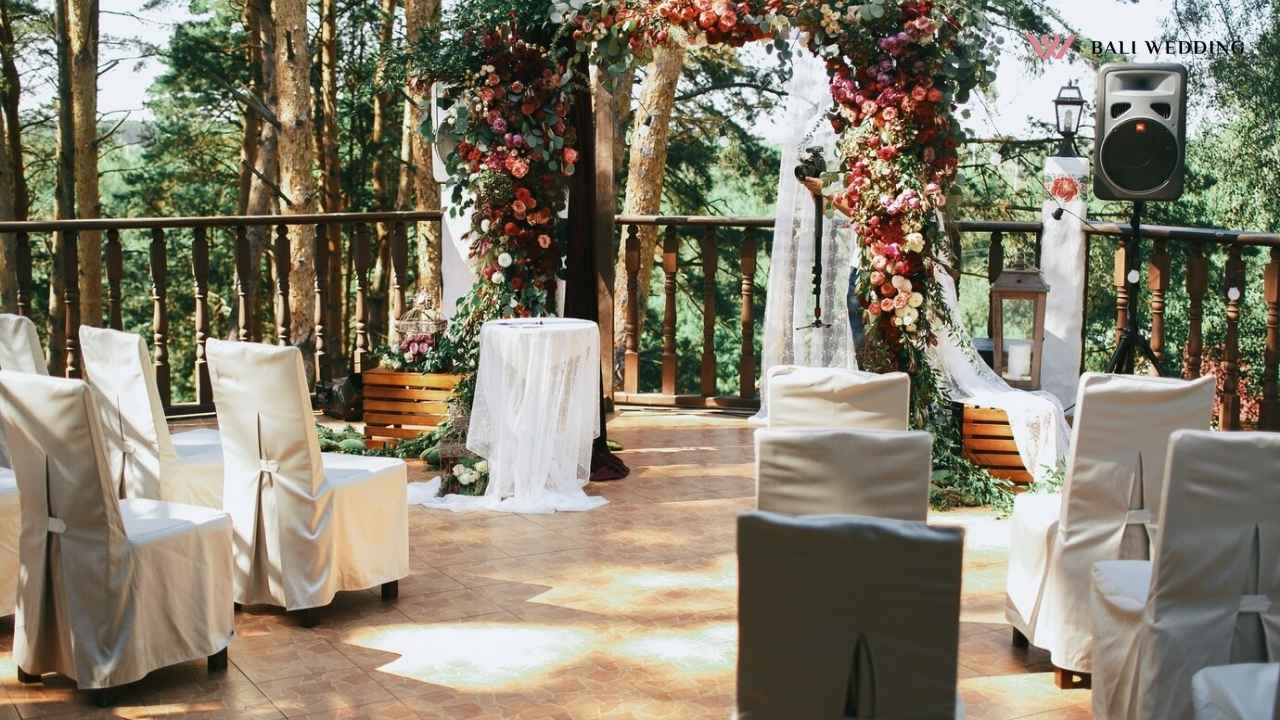 A beautifully decorated wedding altar outdoors, surrounded by nature, with white chairs arranged neatly, ready for guests to witness the wedding ceremony.
