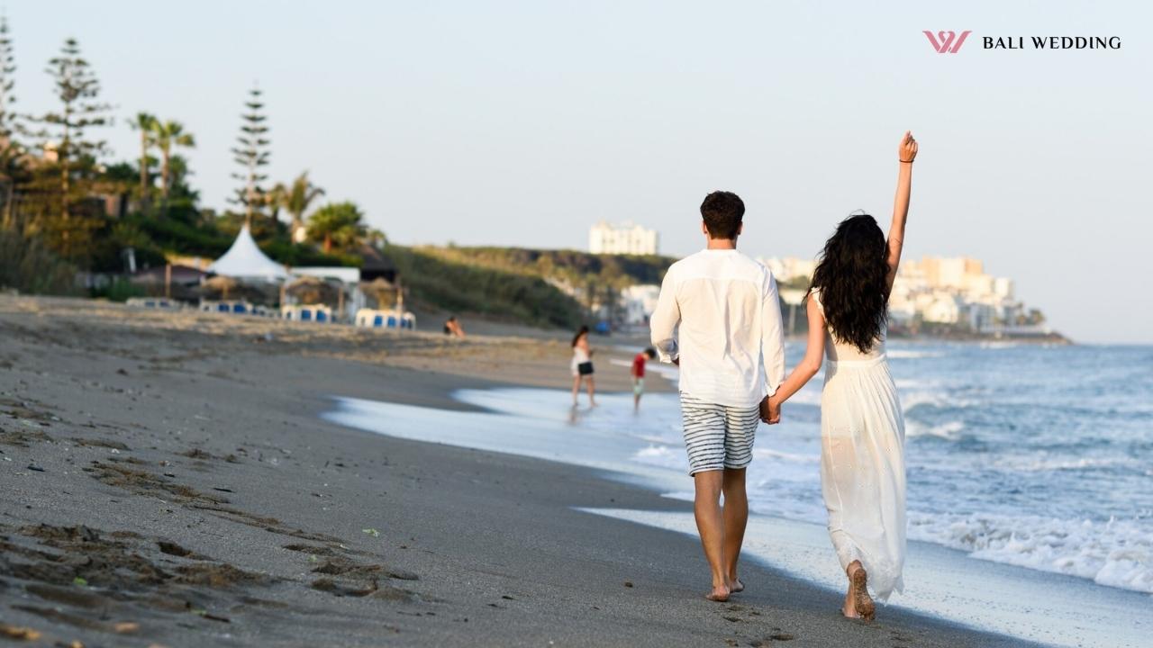 Couple walking hand in hand on a beach.
