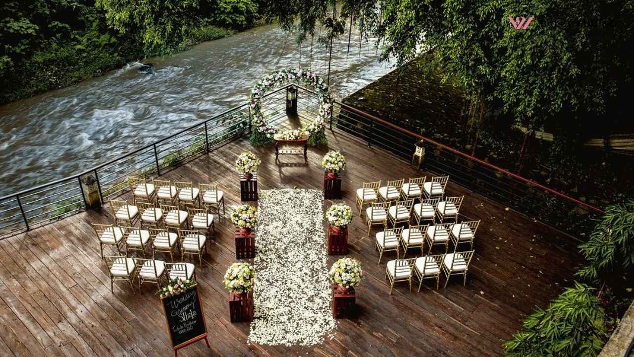 outdoor-wedding-Setup by river with white chairs and a circular flower arch