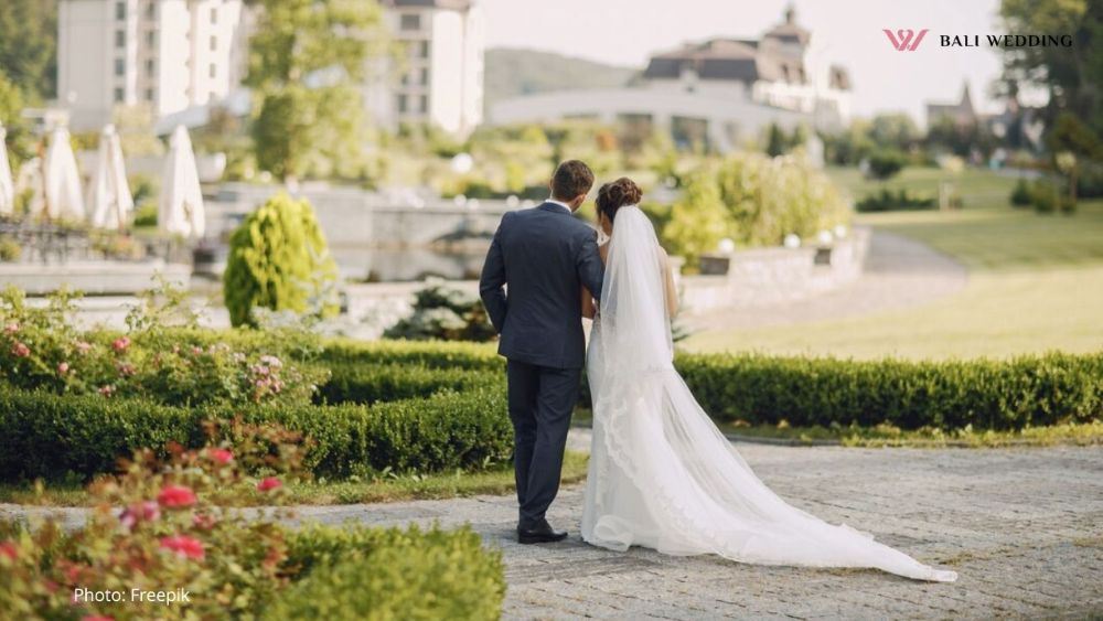 A young and beautiful bride and her husband standing in a park