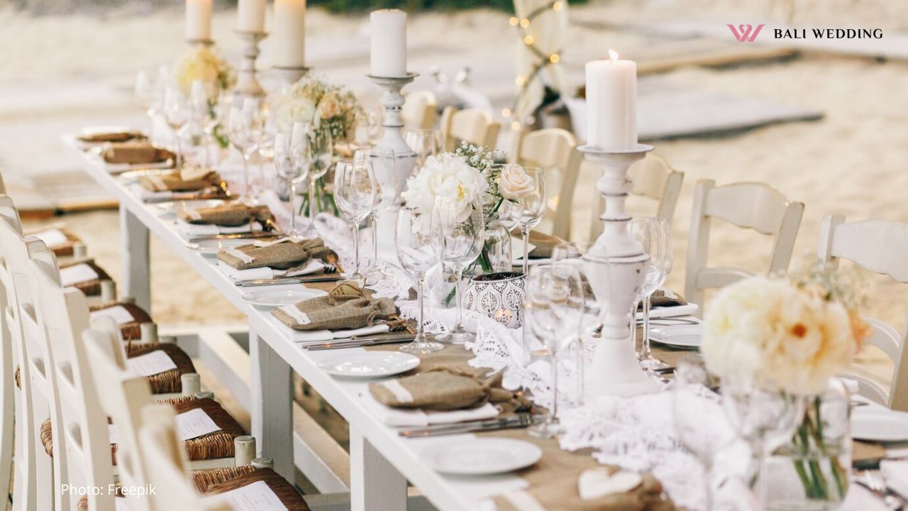 Long dinner table decorated with flaxen cloth and white candles